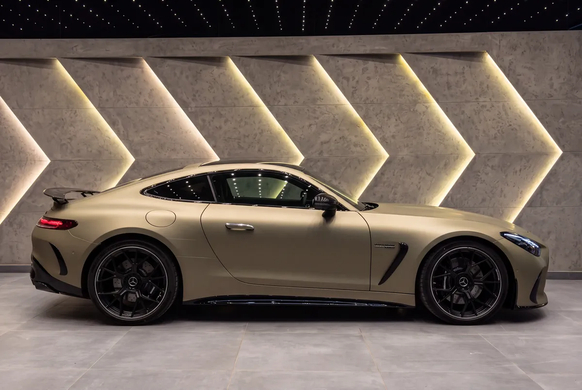 Olive AMG GT coupé against a lit wall